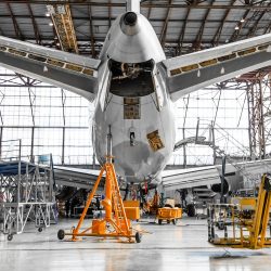 Large passenger aircraft on service in an aviation hangar rear view of the tail.