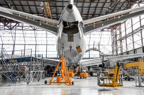 Large passenger aircraft on service in an aviation hangar rear view of the tail.