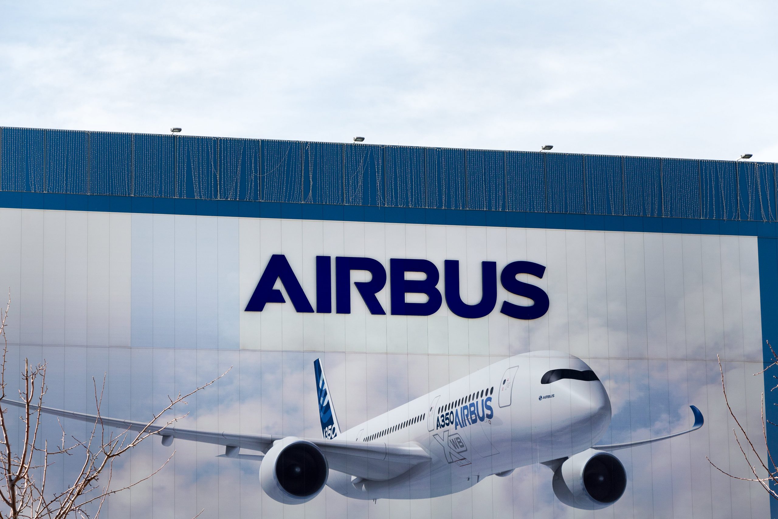 A picture of an Airbus plane taking off with the Airbus logo behind it.