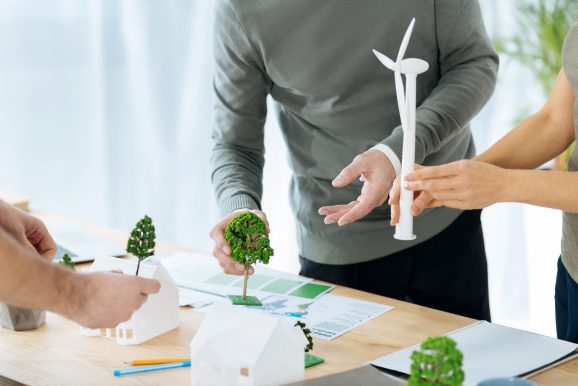 A group of people developing a sustainability plan with miniature figures of trees and houses.