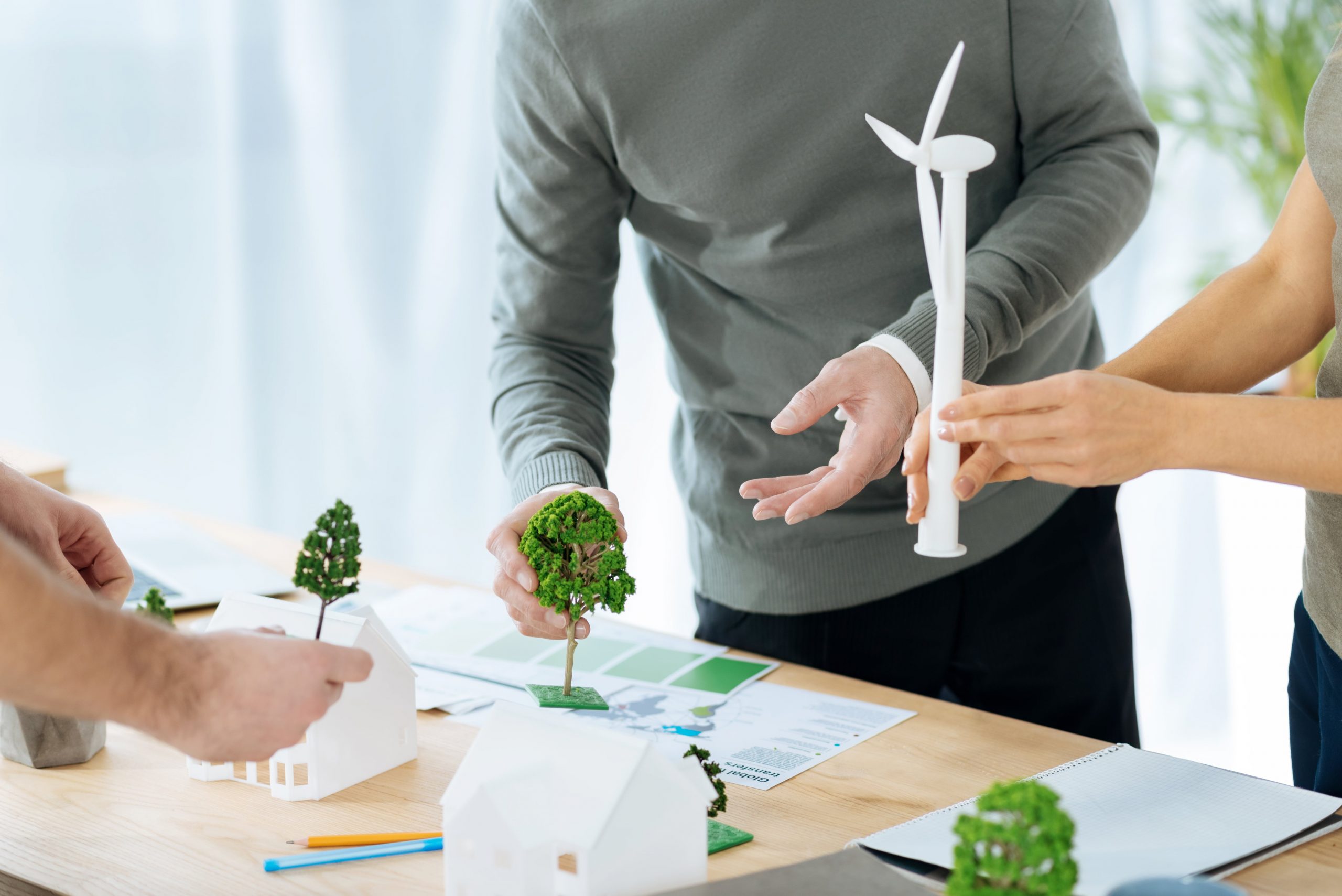 A group of people developing a sustainability plan with miniature figures of trees and houses.
